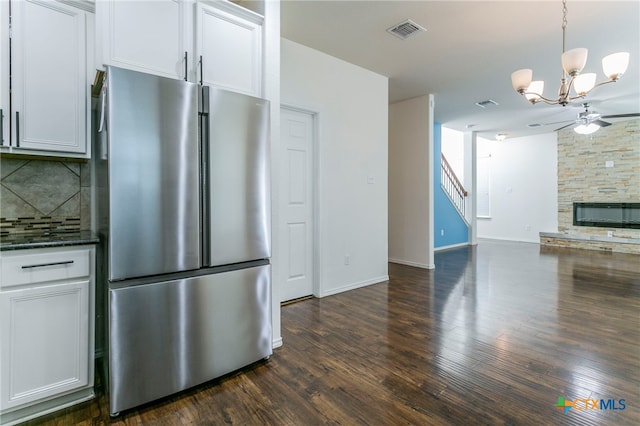 kitchen with dark wood-type flooring, stainless steel refrigerator, and white cabinets