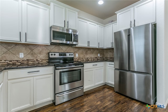 kitchen featuring stainless steel appliances, dark stone counters, white cabinetry, backsplash, and dark hardwood / wood-style floors