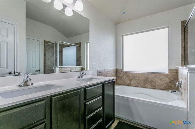 bathroom with shower with separate bathtub, vanity, and vaulted ceiling