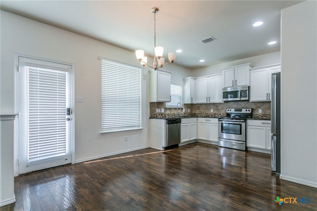 kitchen with stainless steel appliances, dark wood-type flooring, white cabinetry, and pendant lighting