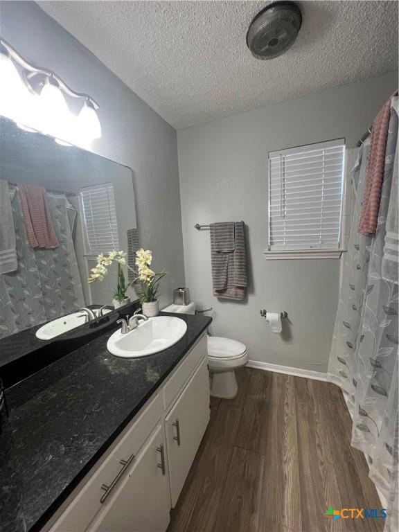 bathroom with hardwood / wood-style flooring, vanity, toilet, and a textured ceiling