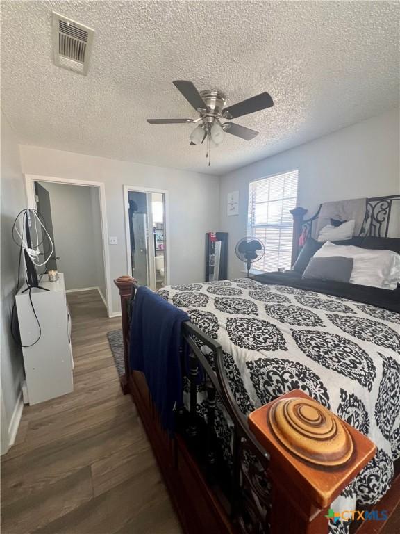 bedroom featuring ceiling fan, dark hardwood / wood-style floors, and a textured ceiling