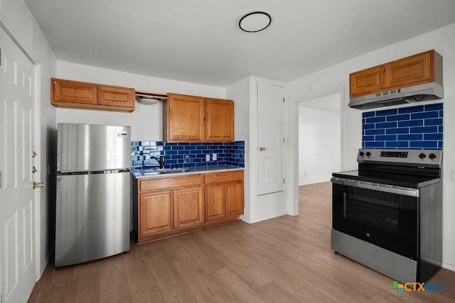 1410 Mulford St, Killeen, TX 76541 - kitchen with stainless steel appliances, under cabinet range hood, light wood-style flooring, brown cabinets, and light countertops