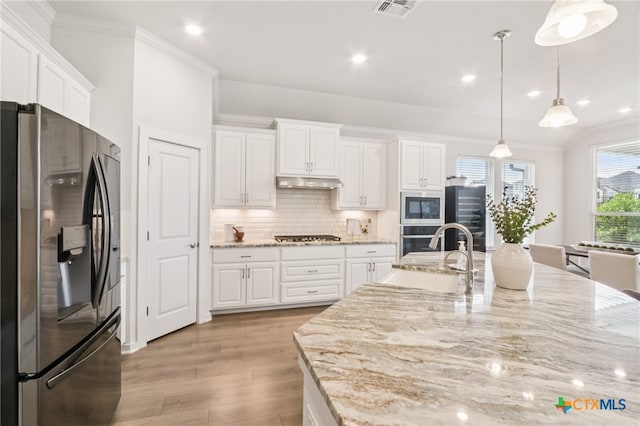 156 High Plains Dr, Georgetown, TX 78628 - kitchen with stainless steel appliances, light wood-type flooring, under cabinet range hood, white cabinets, and decorative backsplash