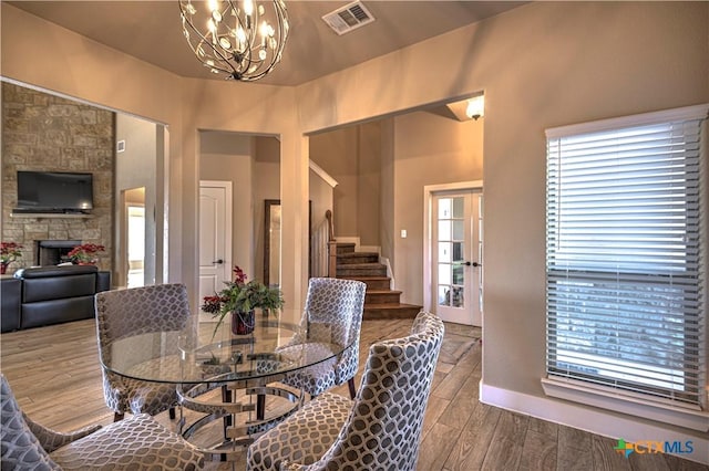 dining area with hardwood / wood-style flooring, a notable chandelier, and a fireplace