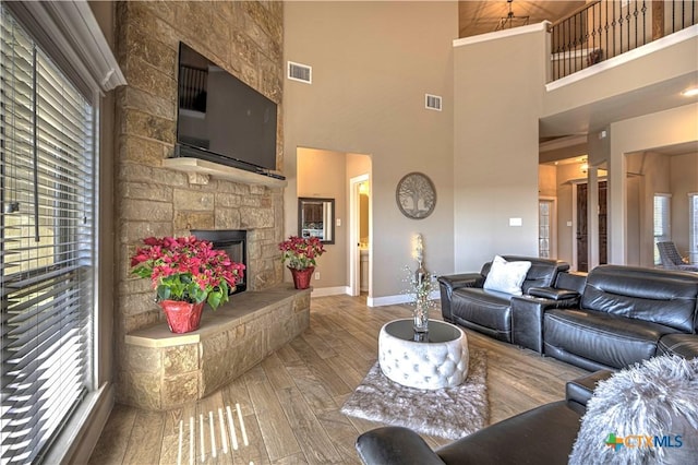 living room with a fireplace, a towering ceiling, and hardwood / wood-style flooring