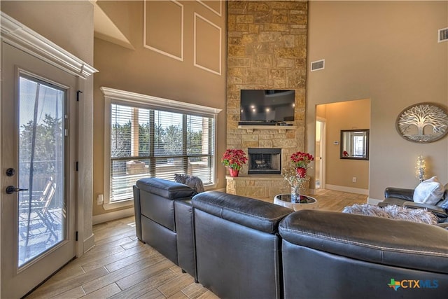 living room featuring a towering ceiling and a stone fireplace