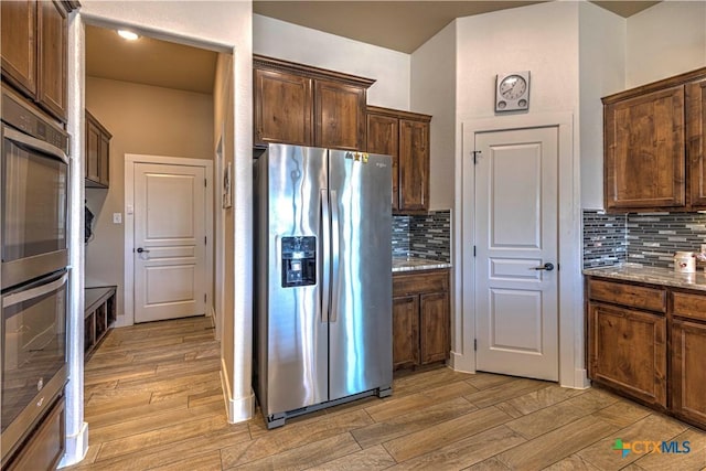 kitchen featuring backsplash, stone counters, and appliances with stainless steel finishes