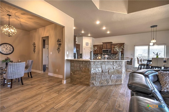 kitchen featuring kitchen peninsula, dark brown cabinets, a textured ceiling, pendant lighting, and light hardwood / wood-style floors