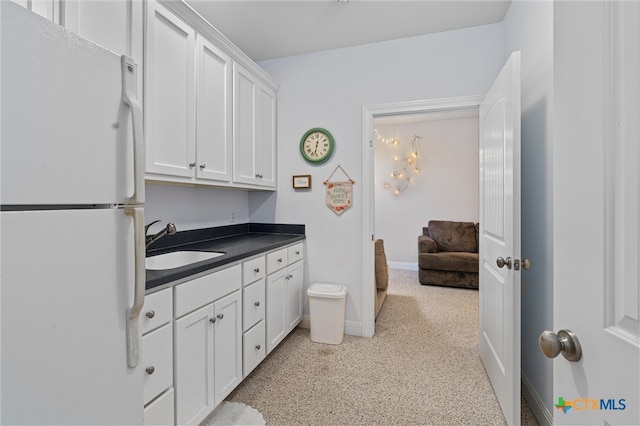 kitchen with white cabinetry, sink, and white fridge