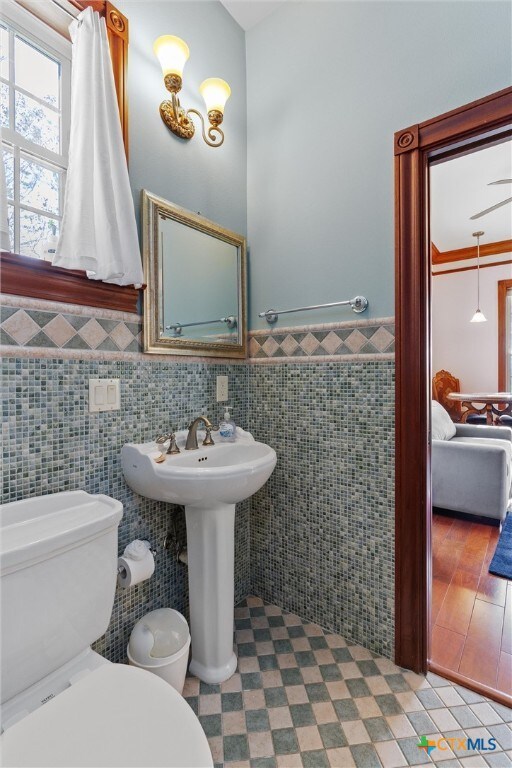 bathroom featuring toilet, tile walls, and sink