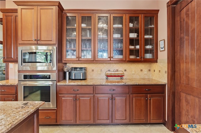 kitchen featuring decorative backsplash, stainless steel appliances, and light stone counters