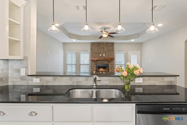 kitchen with tasteful backsplash, sink, a brick fireplace, dishwasher, and a tray ceiling