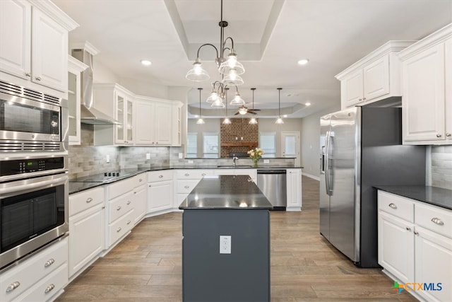 kitchen featuring stainless steel appliances, decorative light fixtures, a center island, and light hardwood / wood-style flooring