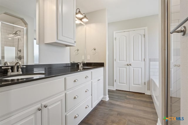 bathroom with hardwood / wood-style floors, a shower with shower door, and vanity