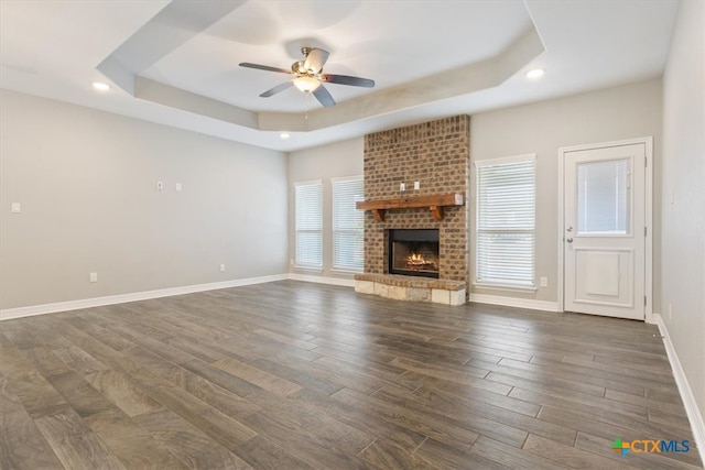 unfurnished living room with dark hardwood / wood-style flooring, a tray ceiling, and plenty of natural light