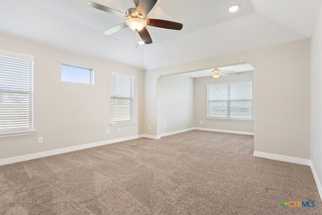 carpeted spare room featuring ceiling fan, vaulted ceiling, and a healthy amount of sunlight