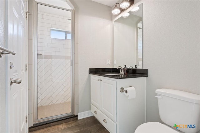 bathroom with a shower with door, wood-type flooring, toilet, and vanity