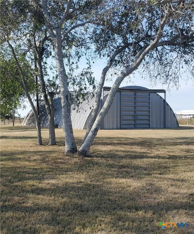 404 S 13th St, Seadrift, TX 77983 - view of grassy yard featuring an outdoor structure, an outbuilding, and a detached garage