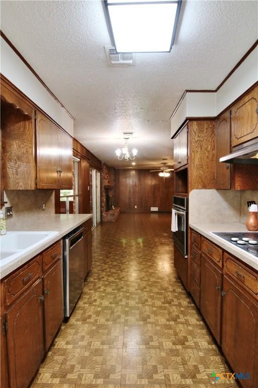 2110 Pamela Rd, Temple, TX 76502 - kitchen featuring appliances with stainless steel finishes, a textured ceiling, a chandelier, under cabinet range hood, and light countertops