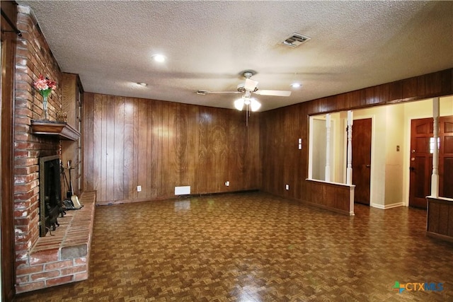 2110 Pamela Rd, Temple, TX 76502 - unfurnished living room with baseboards, wood walls, a ceiling fan, a textured ceiling, and a brick fireplace