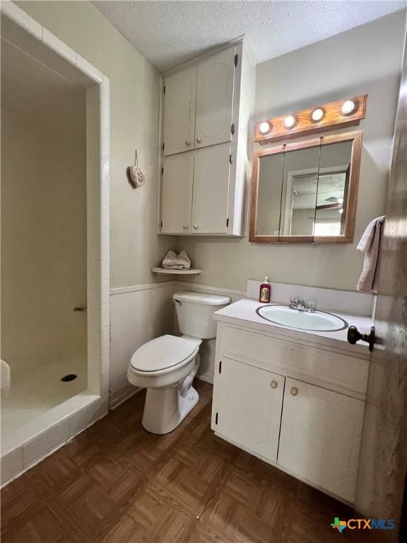 2110 Pamela Rd, Temple, TX 76502 - bathroom with toilet, vanity, a textured ceiling, a shower stall, and wainscoting