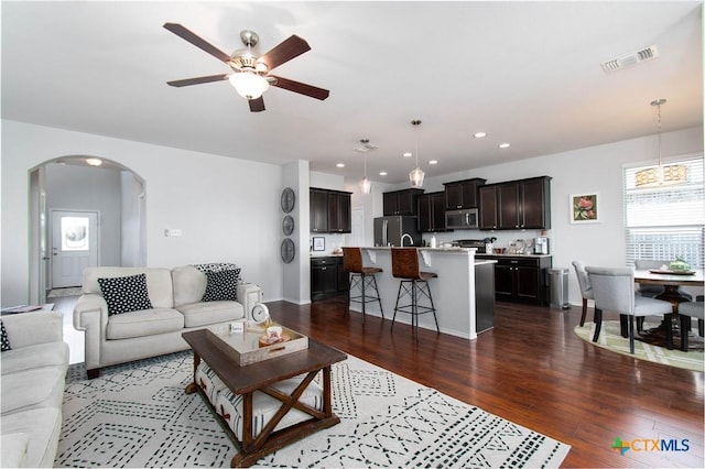 living area with visible vents, arched walkways, a ceiling fan, dark wood-type flooring, and recessed lighting