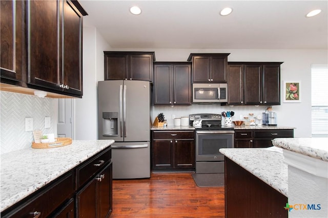 kitchen featuring recessed lighting, appliances with stainless steel finishes, dark wood-type flooring, dark brown cabinetry, and light stone countertops