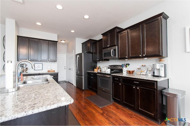 kitchen featuring stainless steel appliances, decorative backsplash, dark wood-type flooring, a sink, and dark brown cabinets