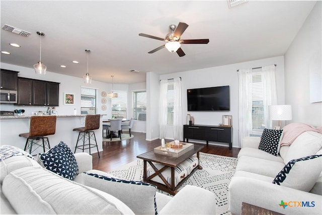 living area featuring a ceiling fan, wood finished floors, visible vents, and recessed lighting