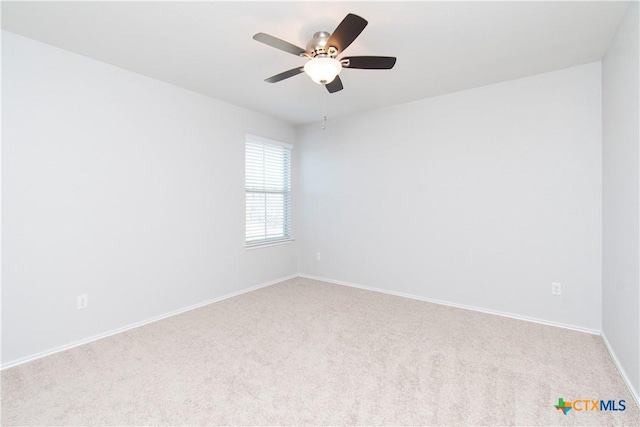 carpeted empty room featuring a ceiling fan and baseboards