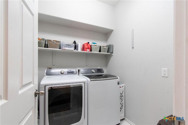 washroom featuring laundry area, baseboards, and washing machine and clothes dryer