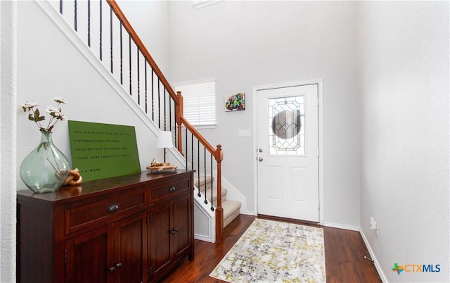 foyer entrance with dark wood-style floors, baseboards, and stairs