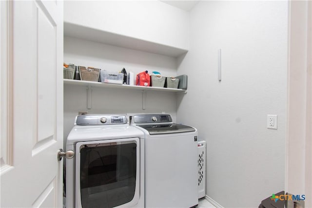 laundry room with laundry area, washing machine and clothes dryer, and baseboards