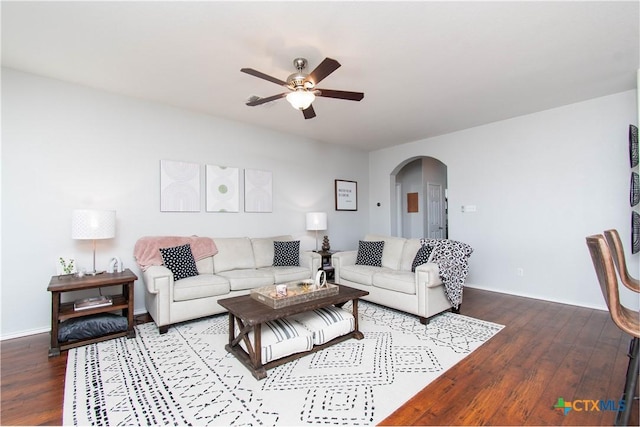 living area featuring arched walkways, ceiling fan, wood finished floors, and baseboards