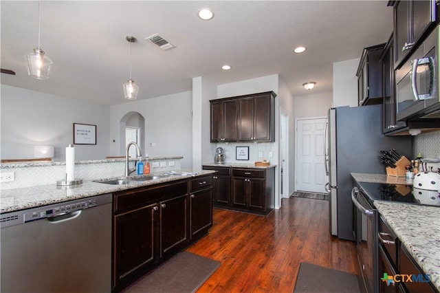 kitchen with arched walkways, stainless steel appliances, a sink, visible vents, and dark wood-style floors