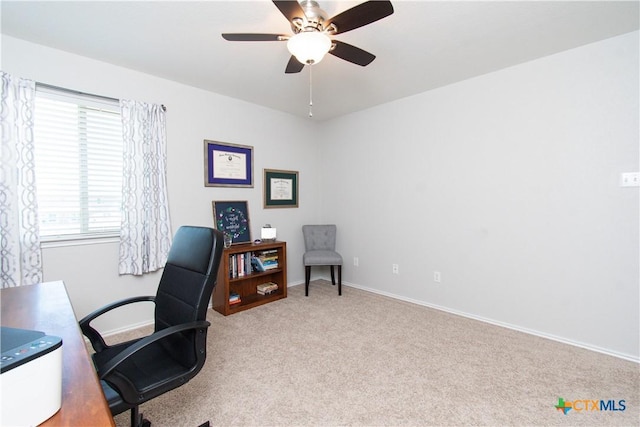 carpeted office featuring a ceiling fan and baseboards