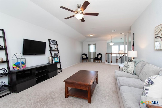 carpeted living room with vaulted ceiling, baseboards, visible vents, and a ceiling fan