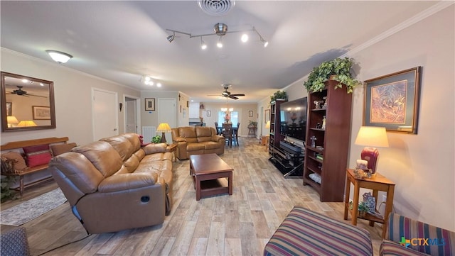 living room with ornamental molding, light wood-type flooring, visible vents, and a ceiling fan