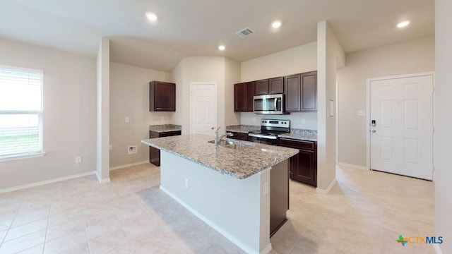 kitchen featuring dark brown cabinetry, visible vents, an island with sink, appliances with stainless steel finishes, and a sink