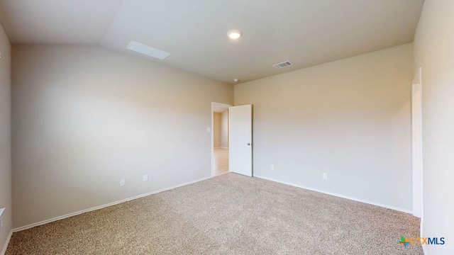 empty room with carpet, visible vents, vaulted ceiling, and baseboards