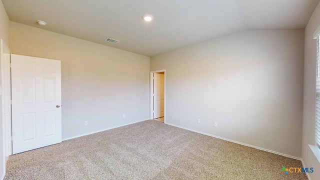 carpeted spare room with lofted ceiling, visible vents, and baseboards