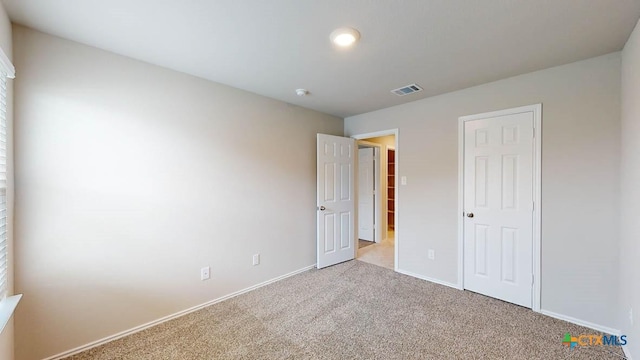 unfurnished bedroom featuring visible vents, light carpet, and baseboards