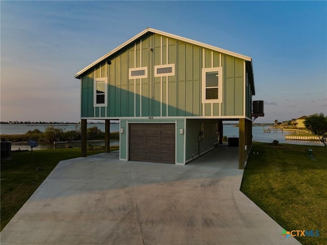 121 Bufflehead Ln, Rockport, TX 78382 - view of front facade featuring board and batten siding, an attached garage, a water view, and a front lawn