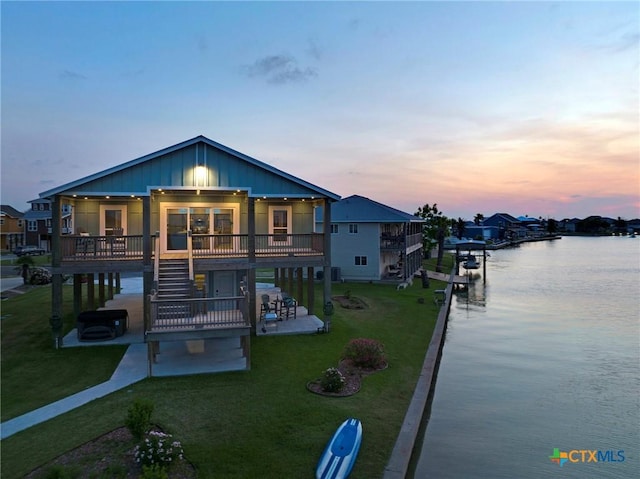 121 Bufflehead Ln, Rockport, TX 78382 - rear view of property with stairway, a patio, a water view, a lawn, and board and batten siding