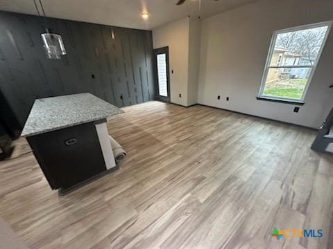 kitchen with light wood-style floors, open floor plan, wood walls, and ceiling fan