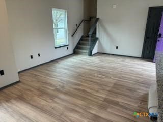 unfurnished living room with stairway and wood finished floors