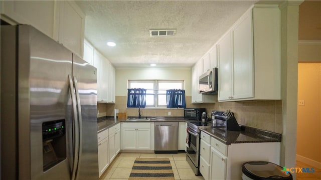 1906 N 60th St, Killeen, TX 76543 - kitchen featuring appliances with stainless steel finishes, a textured ceiling, a sink, white cabinets, and backsplash