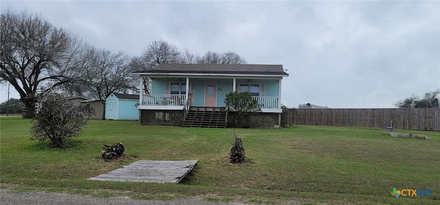 view of front of house featuring a porch, a front yard, and a shed