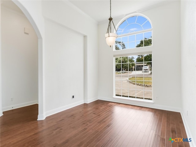 unfurnished dining area with dark hardwood / wood-style flooring, a high ceiling, and ornamental molding